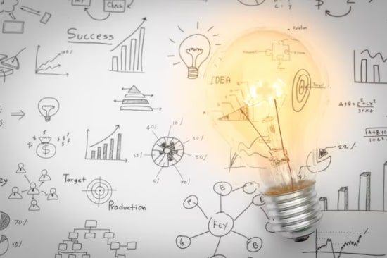 Gráficos de negocios en una pizarra, delante una lamparita encendida